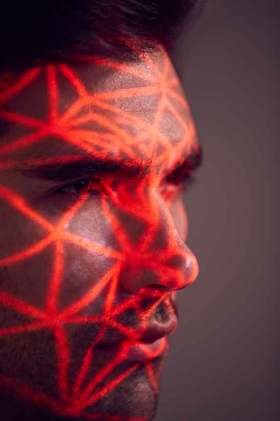 Facial Recognition Technology Concept As Man Has Red Grid Projected Onto Face In Studio