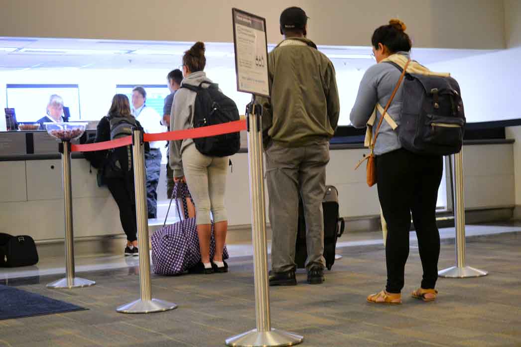 people standing in line at the ticket counter of