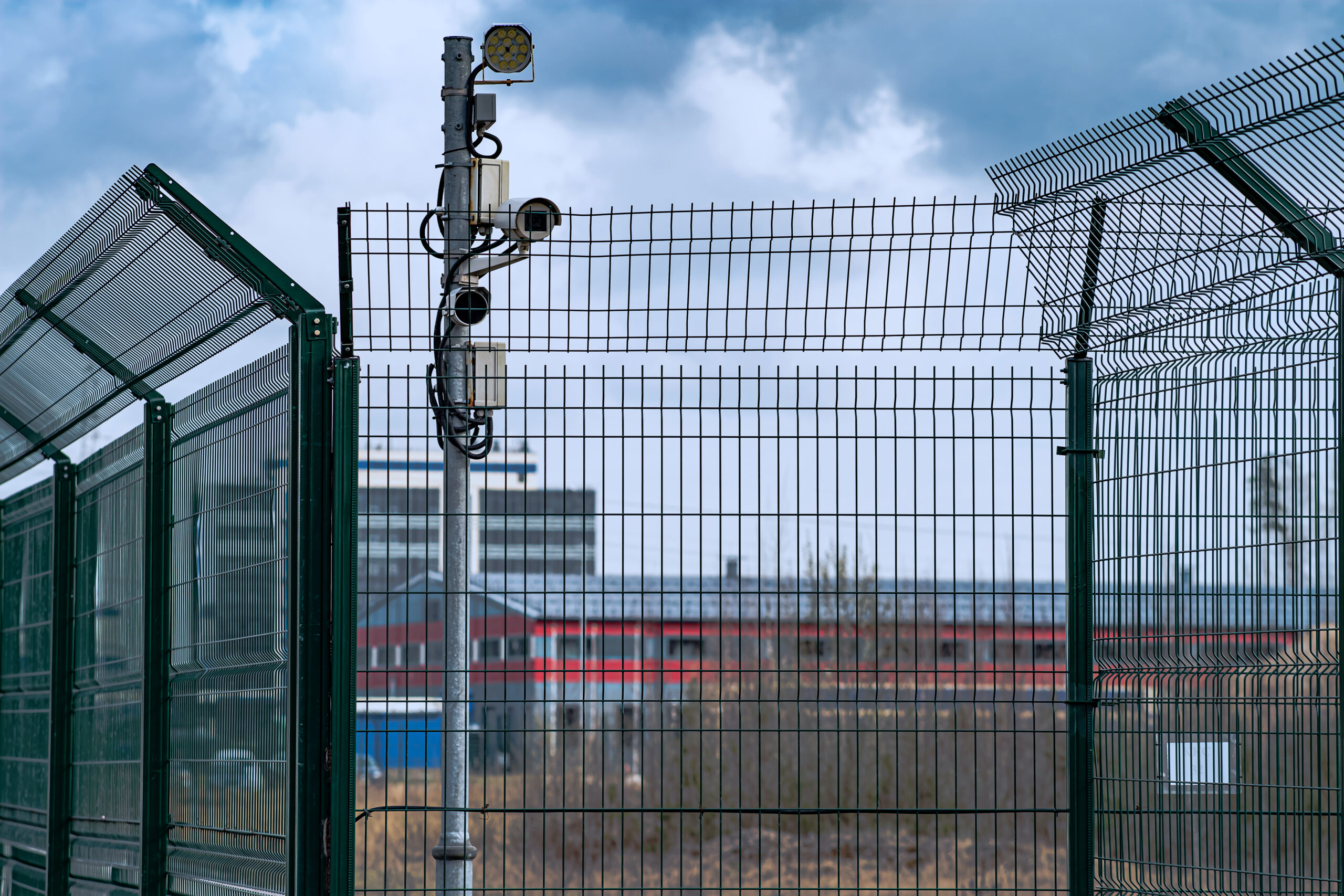 A metal lattice fence and security cameras guard the area. Fence, great design for any purpose. The concept of safety of industrial territories